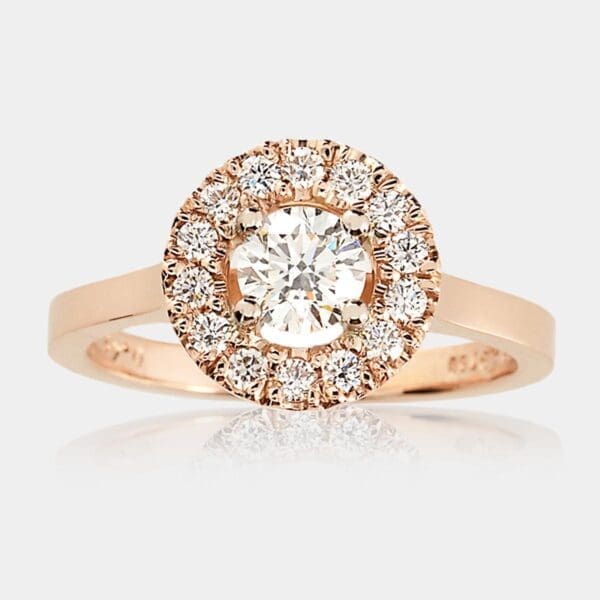 Halo style engagement ring with centre round brilliant cut diamond and surrounding diamonds in flat profile 18ct rose gold band.