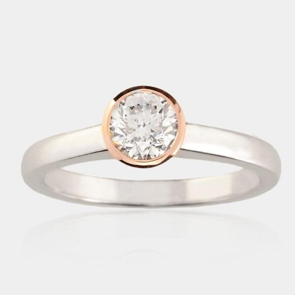 Solitaire diamond engagement ring with rose gold bezel setting and white gold band.