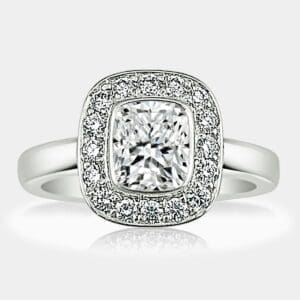 Cushion cut diamond engagement ring with round brilliant cut diamond halo in a plain, white gold band.