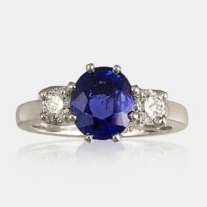 3 stone ring featuring oval cut blue sapphire & 2 x 0.25 carat round brilliant cut diamonds.