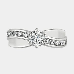 Round brilliant cut diamond engagement ring with wave of channel set diamonds.