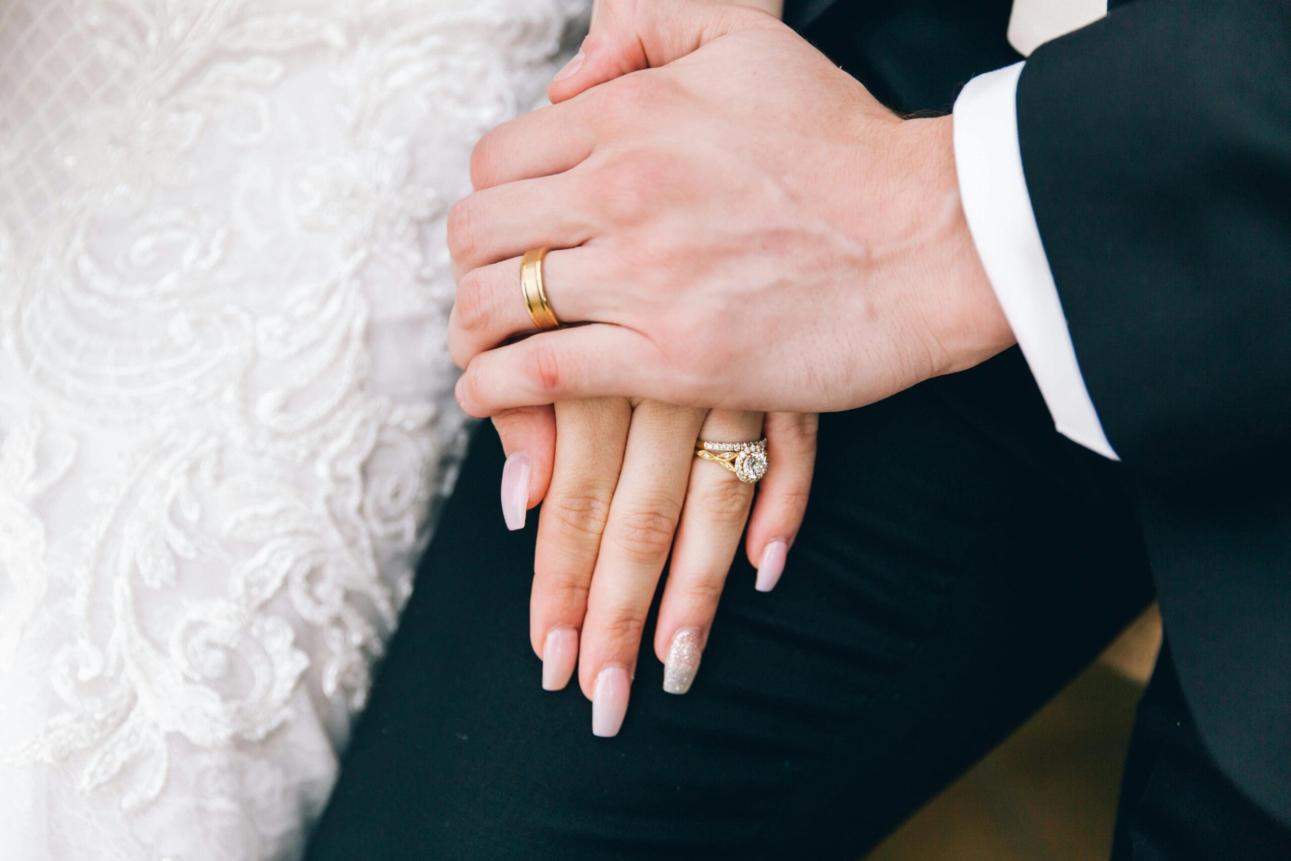 holding hands wearing wedding rings in bridal attire